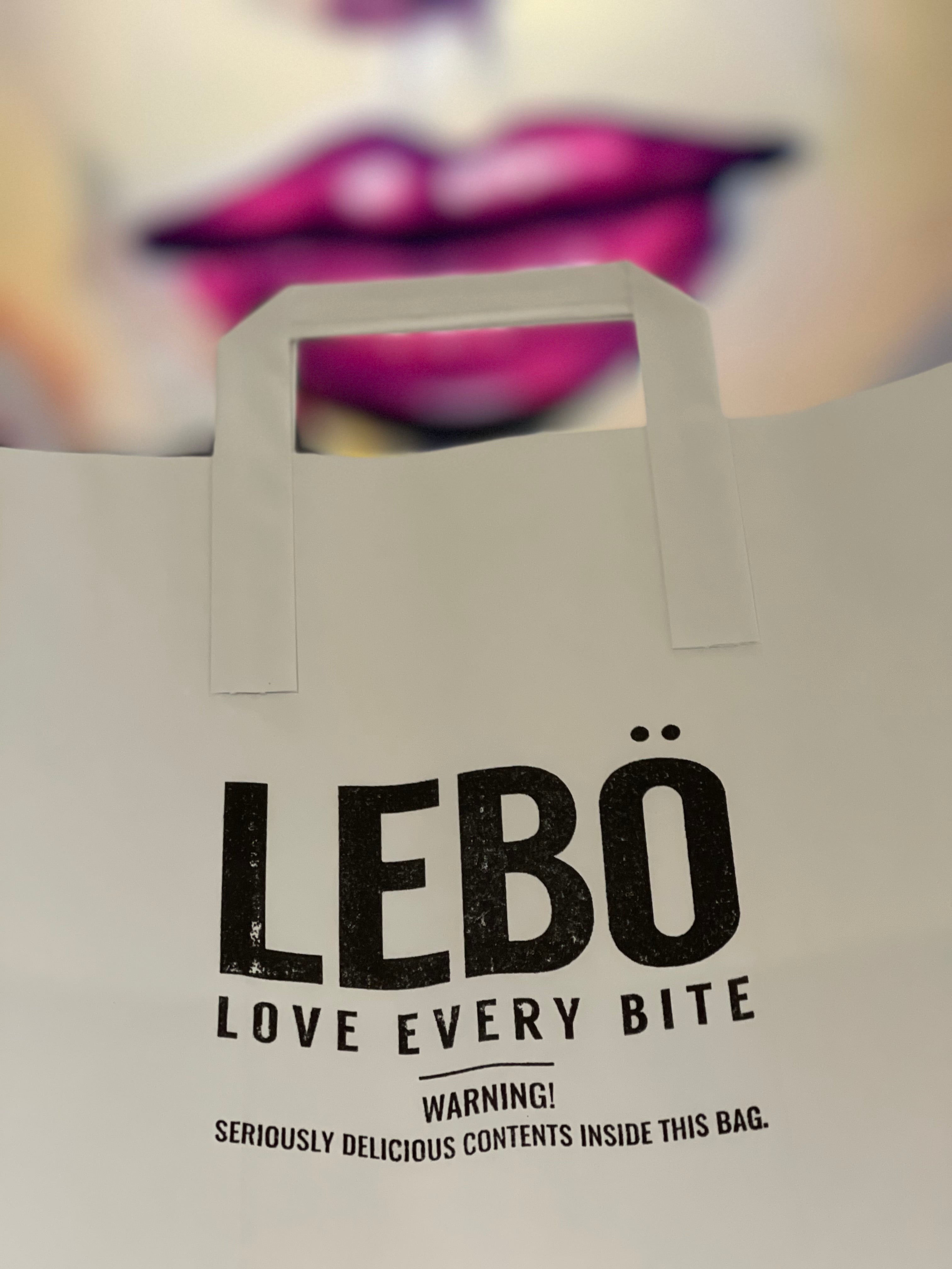 EAT Lebo takeaway bag in front of one of the walls with an image of pink lips.