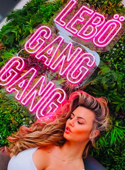 Female posing in front of the EAT LEBO Gang Gang Neon Sign
